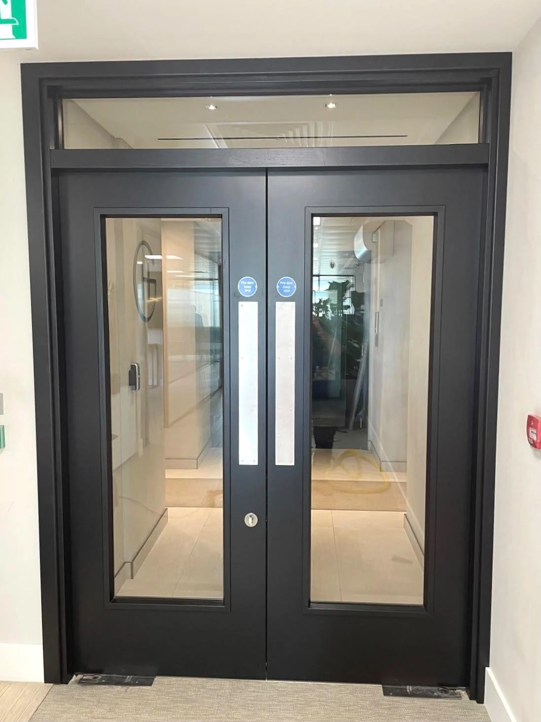 Installed dark grey glazed double fire doors with matching frame, glazed overpanel and metal push plates